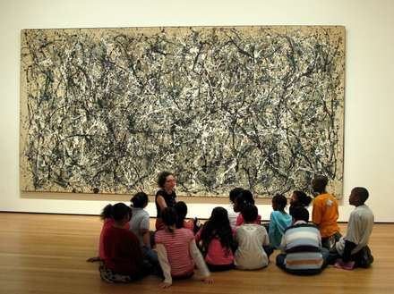 Visitors seated before a large painting in a museum