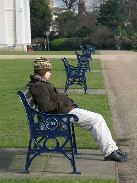 Man reading on a blue bench in a park