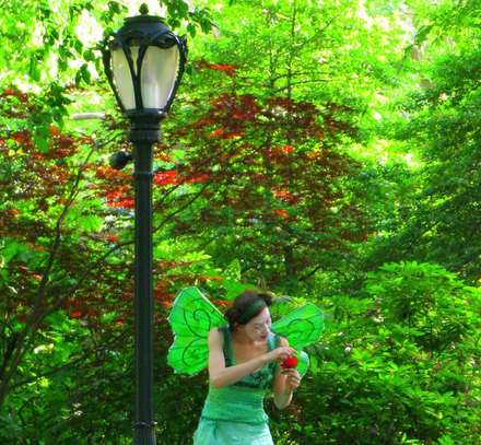 Woman in a green dress beside a streetlamp in a park