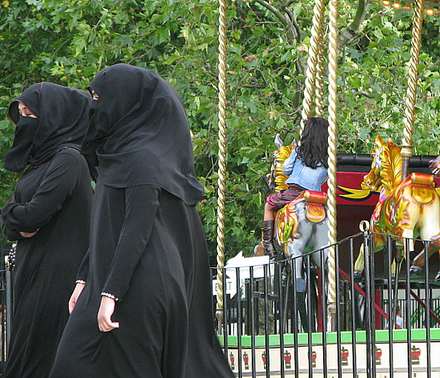 Two veiled women in front of a colourful merry-go-round