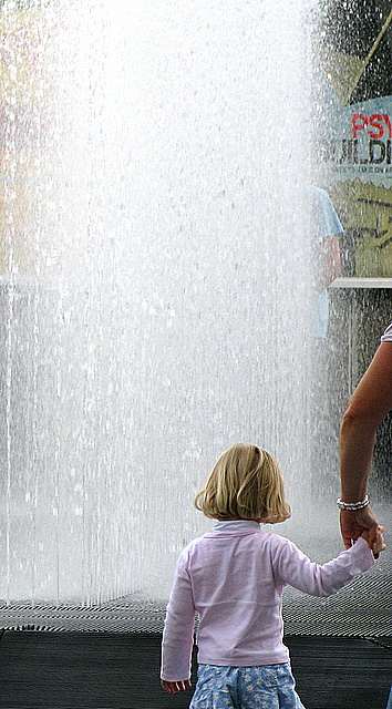 Girl playing in the water of a fountain