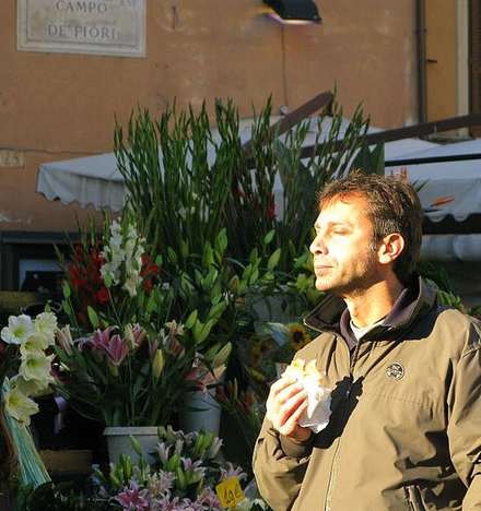 Man in sunlight beside a flower stall